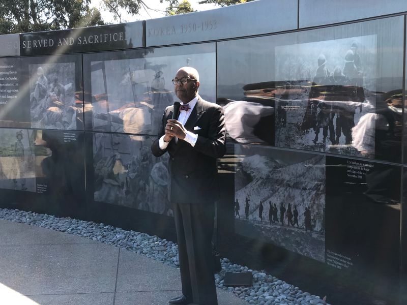 Noah Griffin stands singing in front of the memorial wall